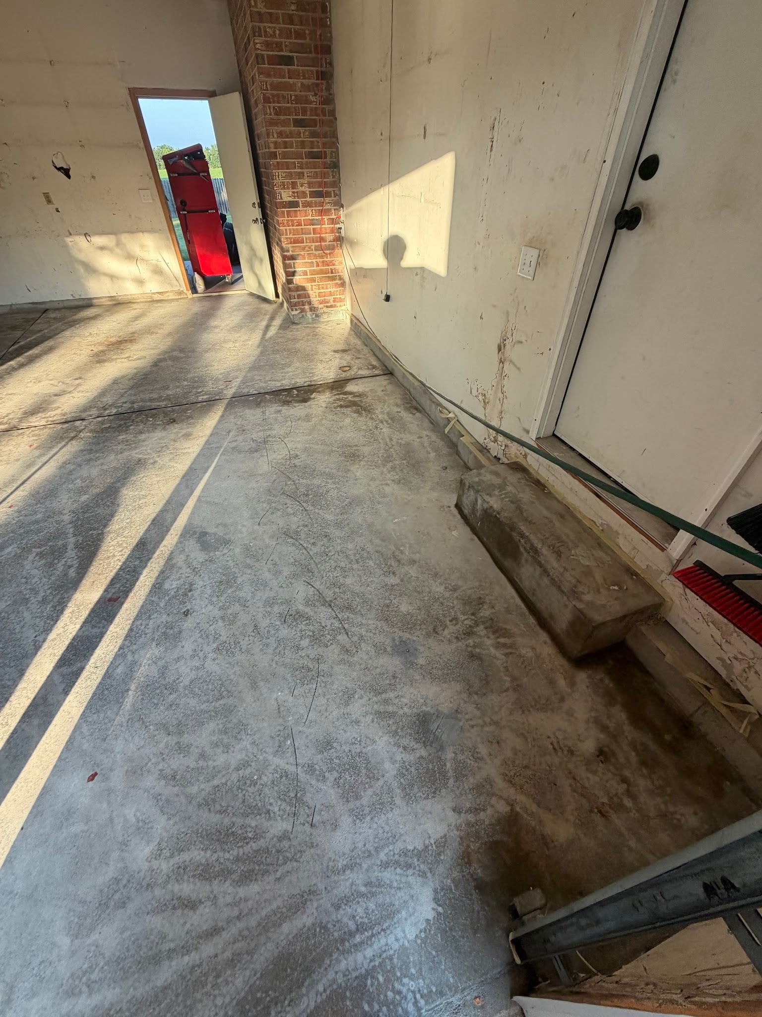 Bare, stained concrete garage floor before ICT Epoxy install